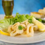 Golden fried calamari with dressed salad and lemon wedge