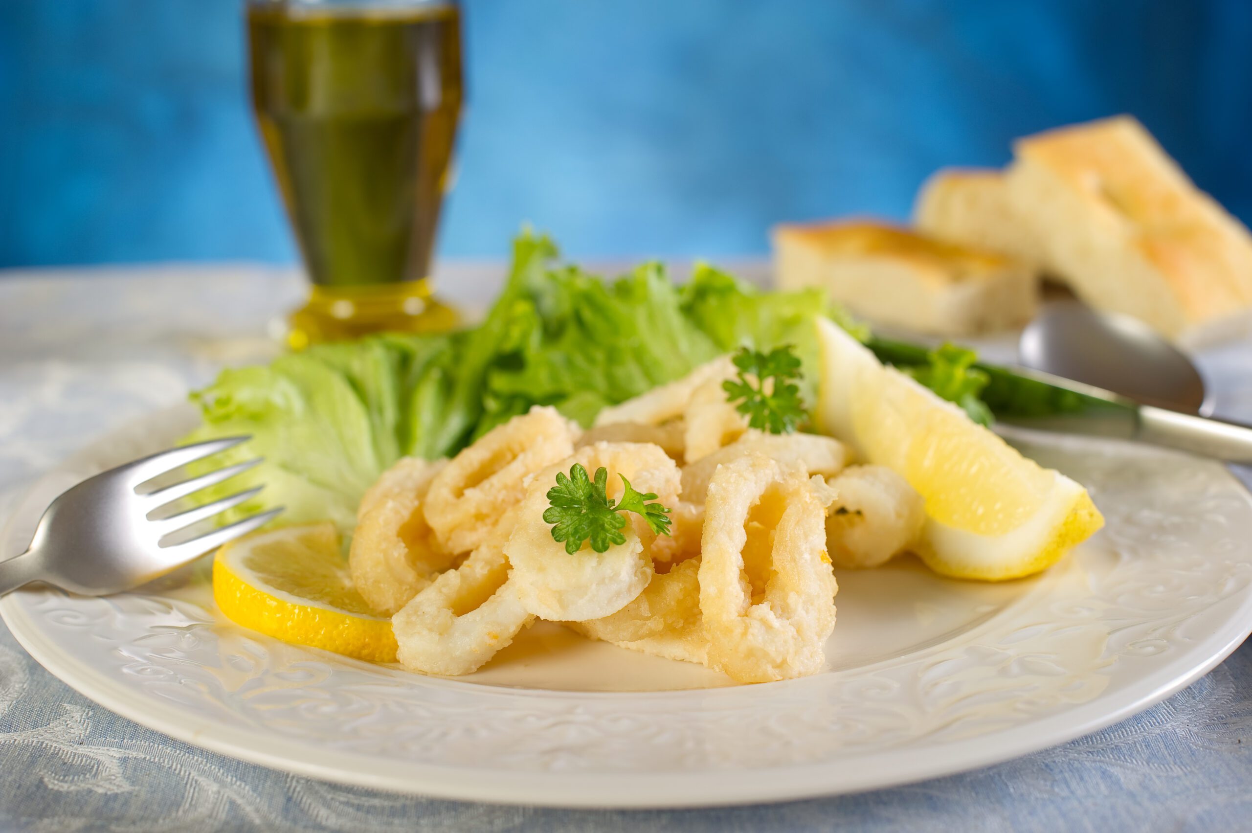 Golden fried calamari with dressed salad and lemon wedge