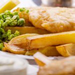 Traditional Battered Hake Fish with french frie mushy peas and tar tar sauce and wedge of lemon