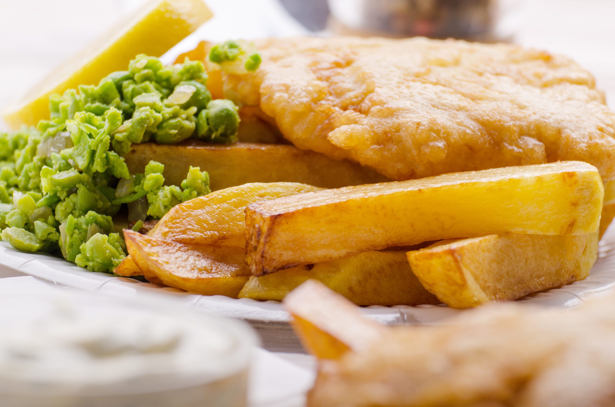 Traditional Battered Hake Fish with french frie mushy peas and tar tar sauce and wedge of lemon